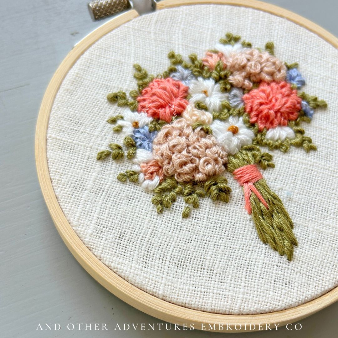 Beautiful Embroidery bouquet with floral embroidery design on a gray surface, featuring 'And Other Adventures Embroidery Co' branding.