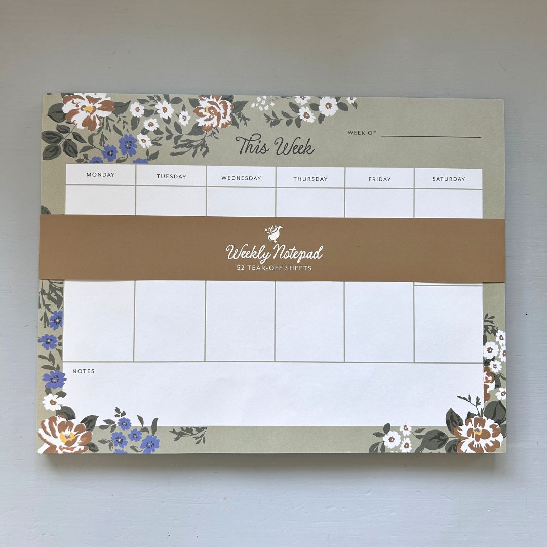 Weekly notepad with floral design on a plain background