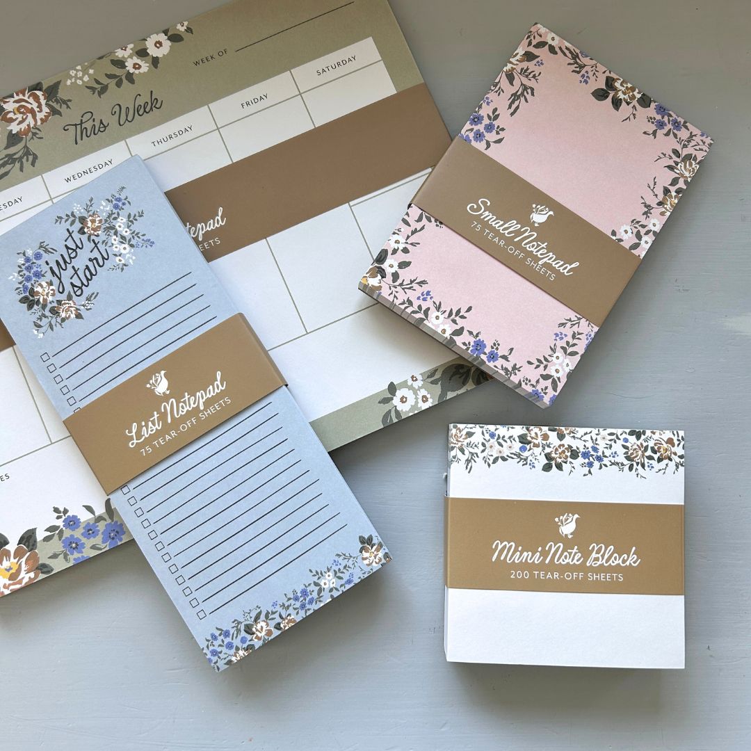 Set of floral-themed notepads and planners on a light gray surface