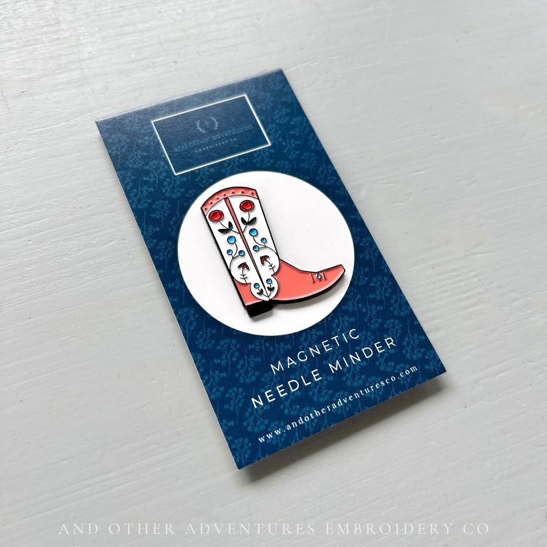 Pink Cowboy boot magnetic needle minder on a blue card designed and sold by And Other Adventures Embroidery Co