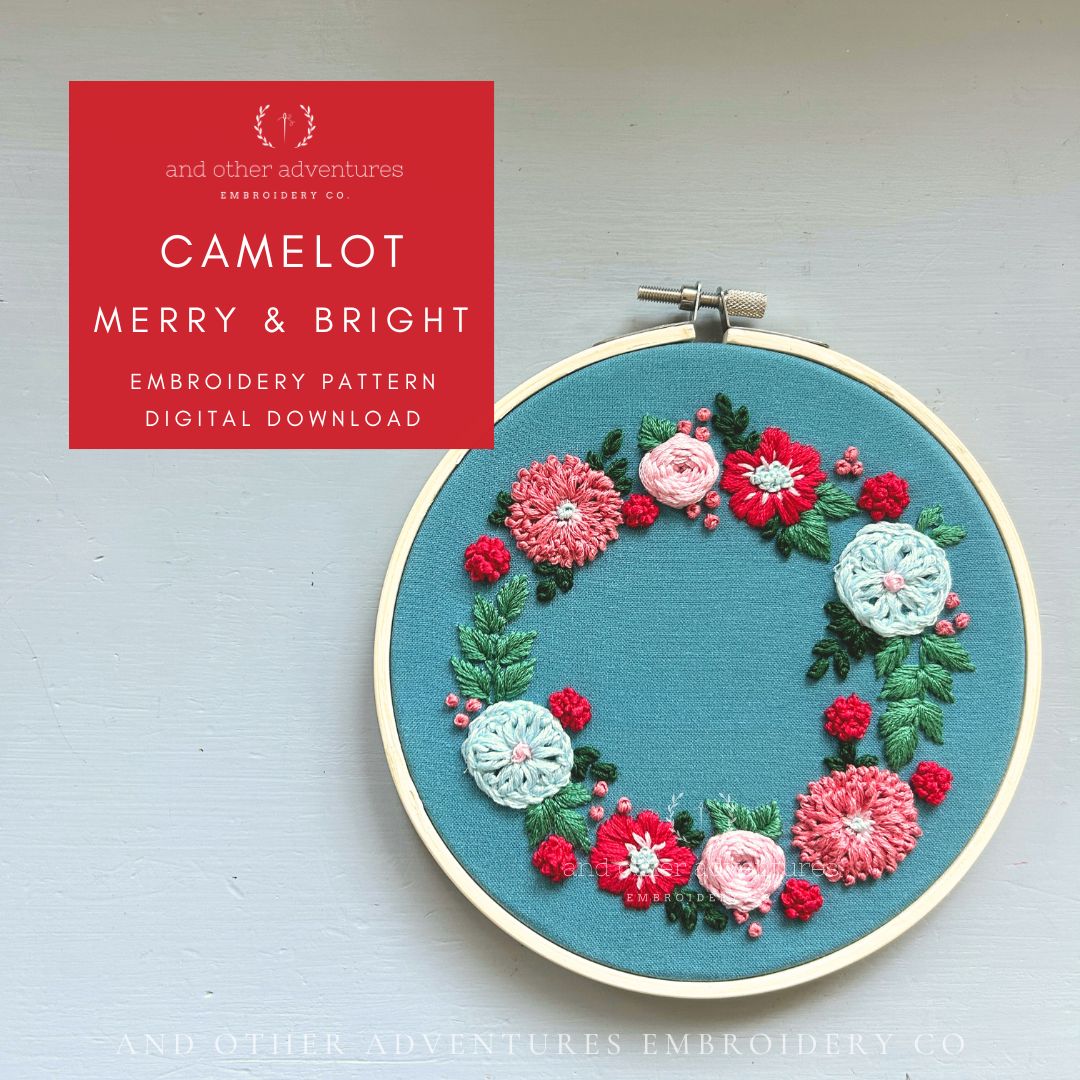 Embroidery hoop with floral design on a light gray background, featuring 'Camelot Merry & Bright' embroidery pattern by And Other Adventures Embroidery Co.