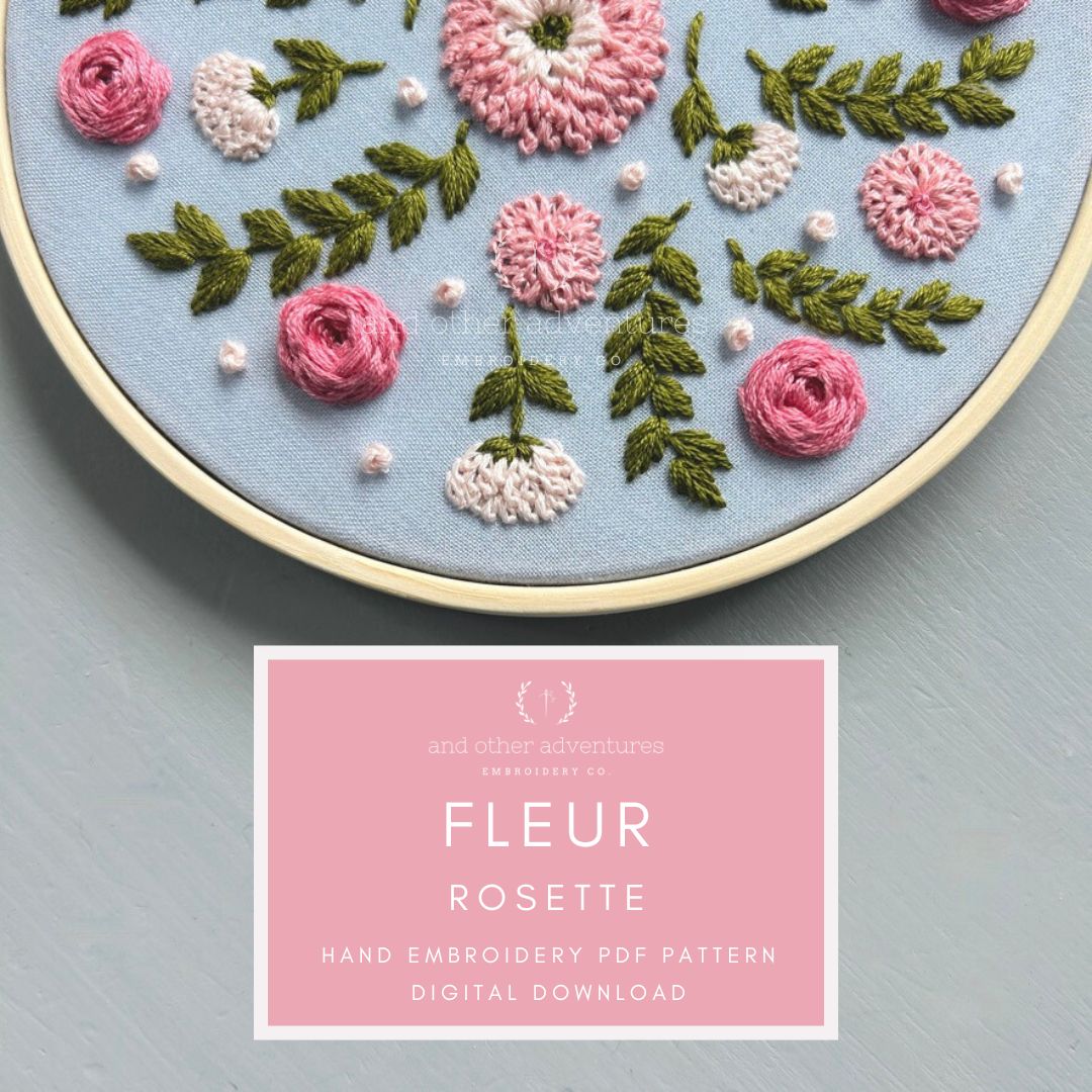 Embroidery hoop with floral design on a blue background, featuring a digital download card for 'Fleur Rosette' pattern.