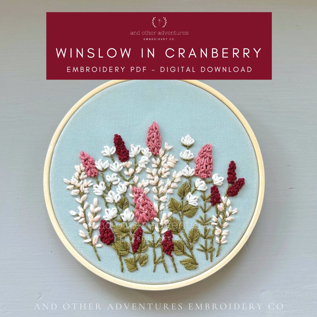 Embroidery hoop with floral design on a light blue background, featuring 'Winslow in Cranberry' embroidery PDF by And Other Adventures Embroidery Co.