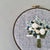 Hand Embroidered Blue Green and White bouquet hand stitched on to blue linen by And Other Adventures Embroidery Co